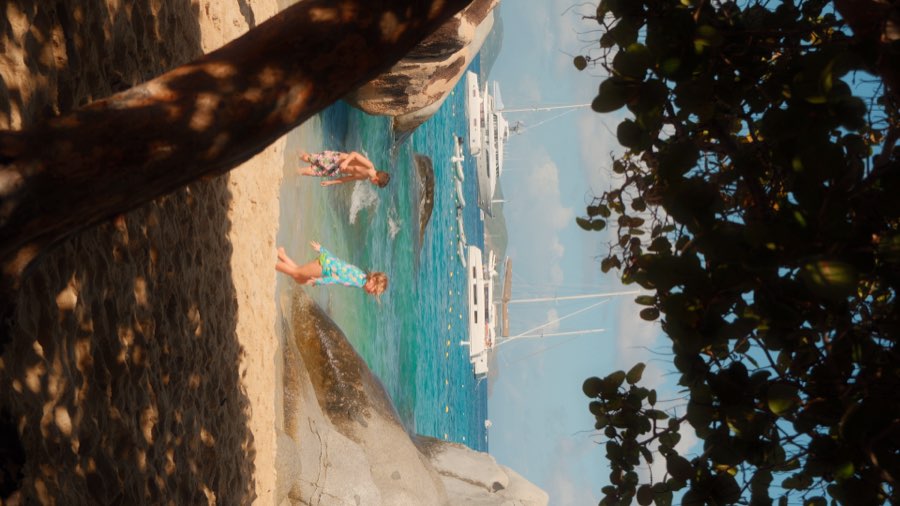Turquoise bay with boats and kids playing on the shore, British Virgin Islands