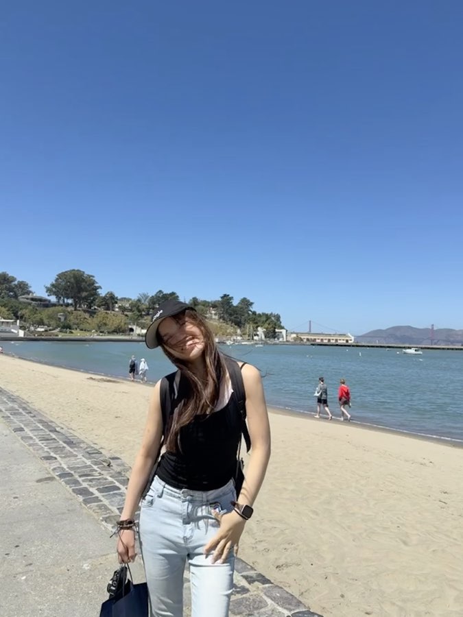 Standing by the beach in California with the Golden Gate Bridge in the distance